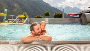 A swimming pool with a mountain backdrop, a diving board, and a covered seating area. - Spacious Stay With Mountain View (Wald im Pinzgau)