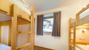 A room with bunk beds, a window with curtains, and a view of a building outside. - Spacious Stay With Mountain View (Wald im Pinzgau)