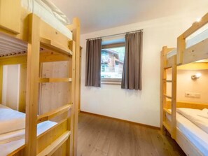 A room with bunk beds, a window with curtains, and a view of a building outside. - Spacious Stay With Mountain View (Wald im Pinzgau)