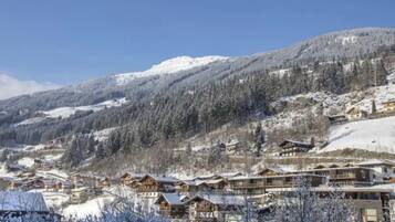 Un village de montagne enneigé, avec des bâtiments en bois et un ciel bleu azur.