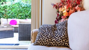 A living room with a sofa, a leopard print pillow, and a vase of flowers. - Apartment in Oostkapelle Near the Beach (Oostkapelle)