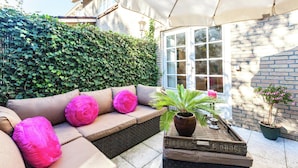 An outdoor seating area with a cushioned bench, a potted plant, and a wicker tray. - Apartment in Oostkapelle Near the Beach (Oostkapelle)