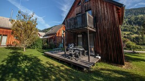 A rustic wooden house with a balcony, a deck with outdoor furniture, and a mountainous backdrop. - Holiday Home on the Kresichberg With Swimming Pool (Sankt Georgen am Kreischberg)