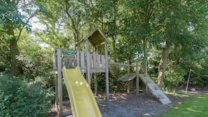 A wooden playground with a yellow slide and climbing structures. - Luxurious Mansion in Callantsoog With Sauna (Callantsoog)