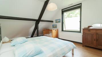 Un dormitorio con cama, cabecera de madera, ventana con vistas, armario de madera y una lámpara colgante.