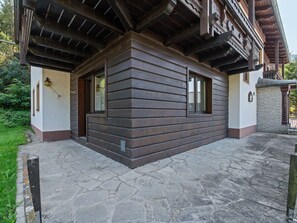 A wooden cabin with a stone-paved entrance, a small porch, and a window. - Cushy Apartment in Bad Kleinkirchheim near Ski Area (Bad Kleinkirchheim)