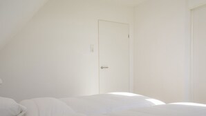 A room with a bed, a door, and a light switch on the wall.