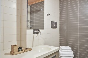 A bathroom with a white sink, a mirror, a towel rack, and a shower area. - Contemporary Comfy Apt (Athens)