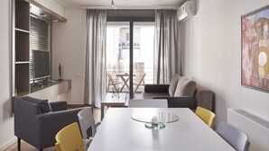 Una sala de estar moderna con una mesa de comedor, sofás y un ventanal con cortinas.