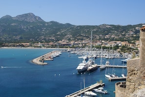 A marina with boats docked, a stone wall, and a mountainous backdrop. - Holiday Home in Corsica by the Sea (Poggio-Mezzana)