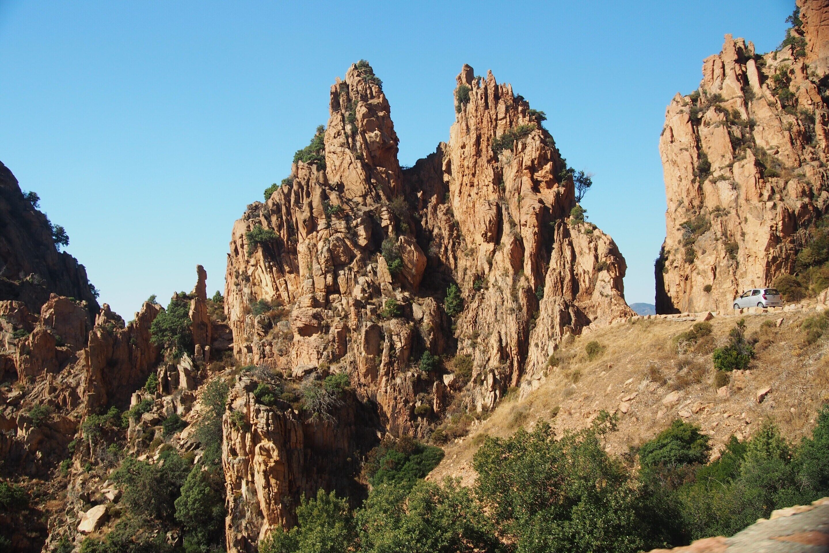 A rugged mountain landscape with rocky cliffs and sparse vegetation.