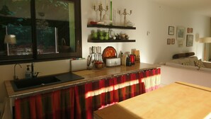 A kitchen with a window, a sink, a countertop, and a dining area with a table. - Villa in Bruniquel by Aveyron River (Bruniquel)
