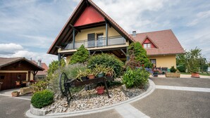 A two-story house with a balcony, surrounded by a garden with various plants and a decorative wheel. - Holiday Home in Ruederbach Near Lake (Ruederbach)