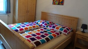Ein Schlafzimmer mit einem Holzbett, einem Holzschrank und einem farbenfrohen Bild an der Wand.