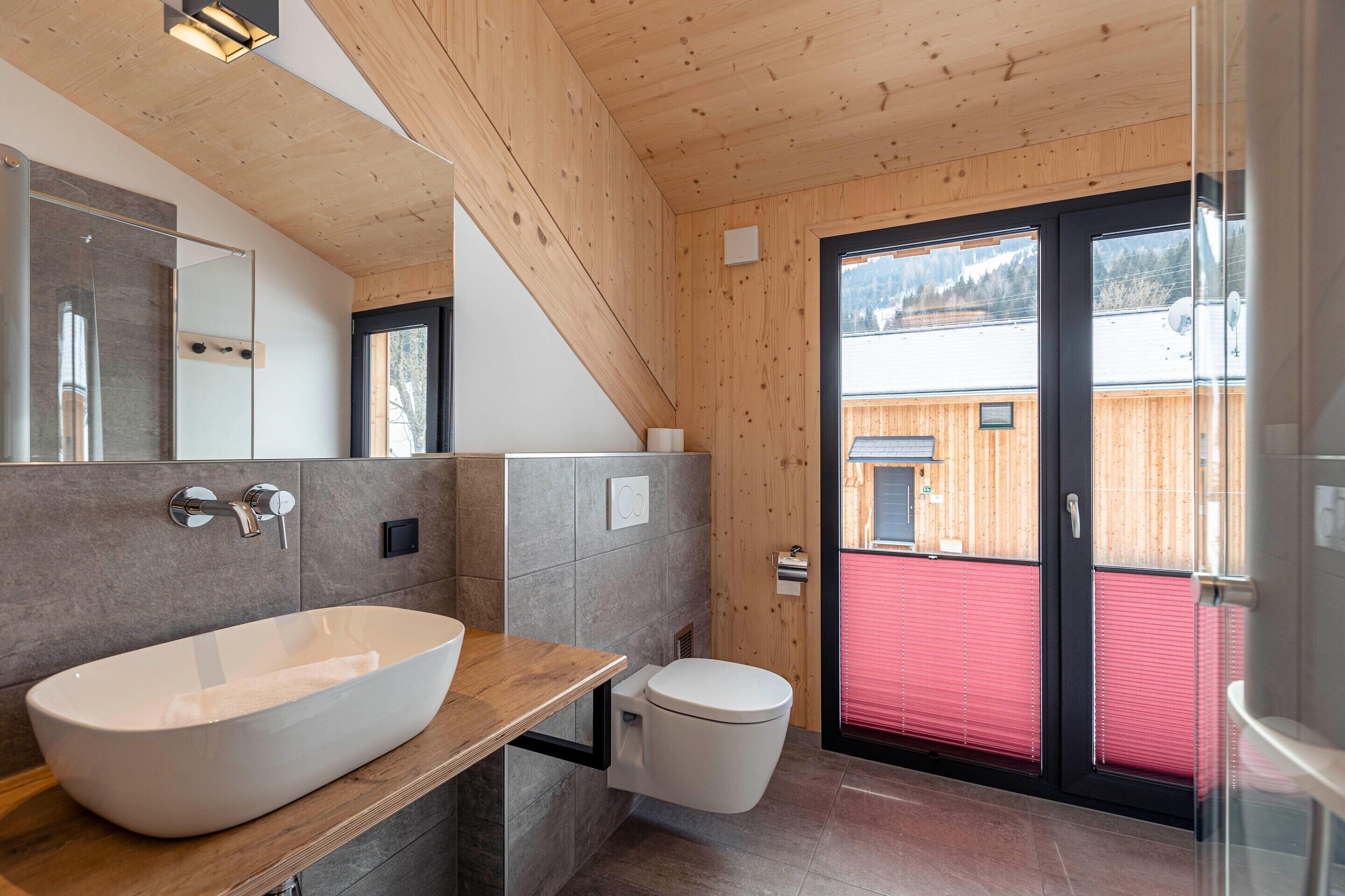 A modern bathroom with a large vessel sink, a toilet, and a glass shower enclosure.