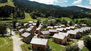 A cluster of wooden cabins with sloped roofs, arranged in rows with a dirt road in front.