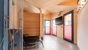 A modern interior with wooden walls, a bench, a television, and a door with a red shutter.