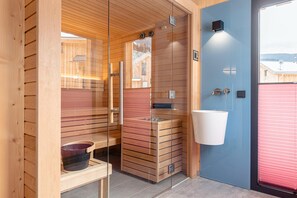 A sauna room with wooden walls, a glass door, and a sink. - Nice Chalet With hot tub (Sankt Georgen am Kreischberg)