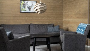 Una sala de estar moderna con un sofá seccional gris, una mesa de centro redonda y una lámpara colgante de madera original.
