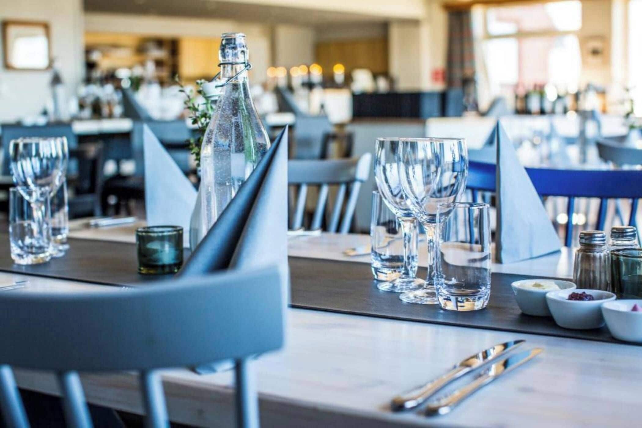 A dining area with tables set for service, including glasses, cutlery, and condiments.