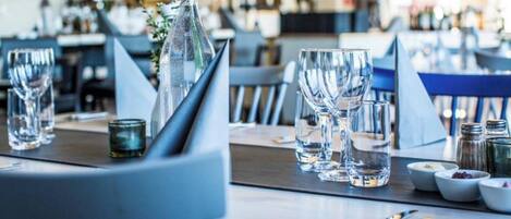 A dining area with tables set for service, including glasses, cutlery, and condiments.