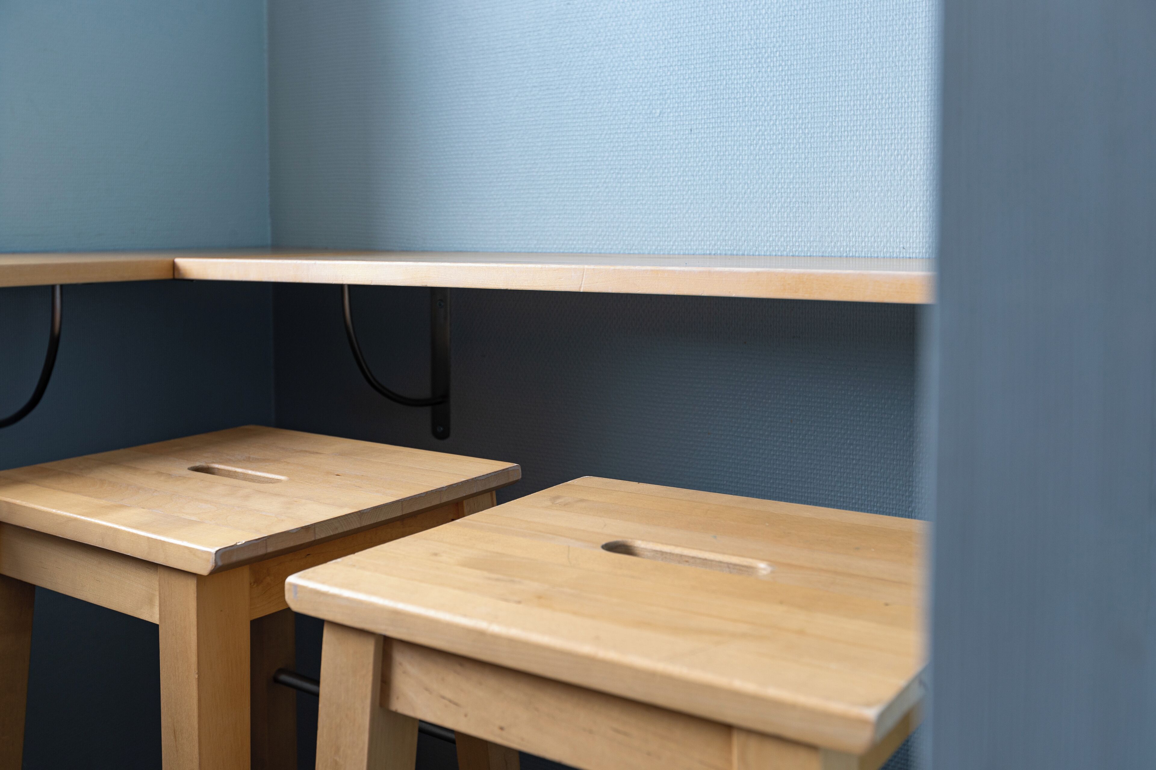 Zwei Holztische mit Metallbeinen vor einer blauen Wand.