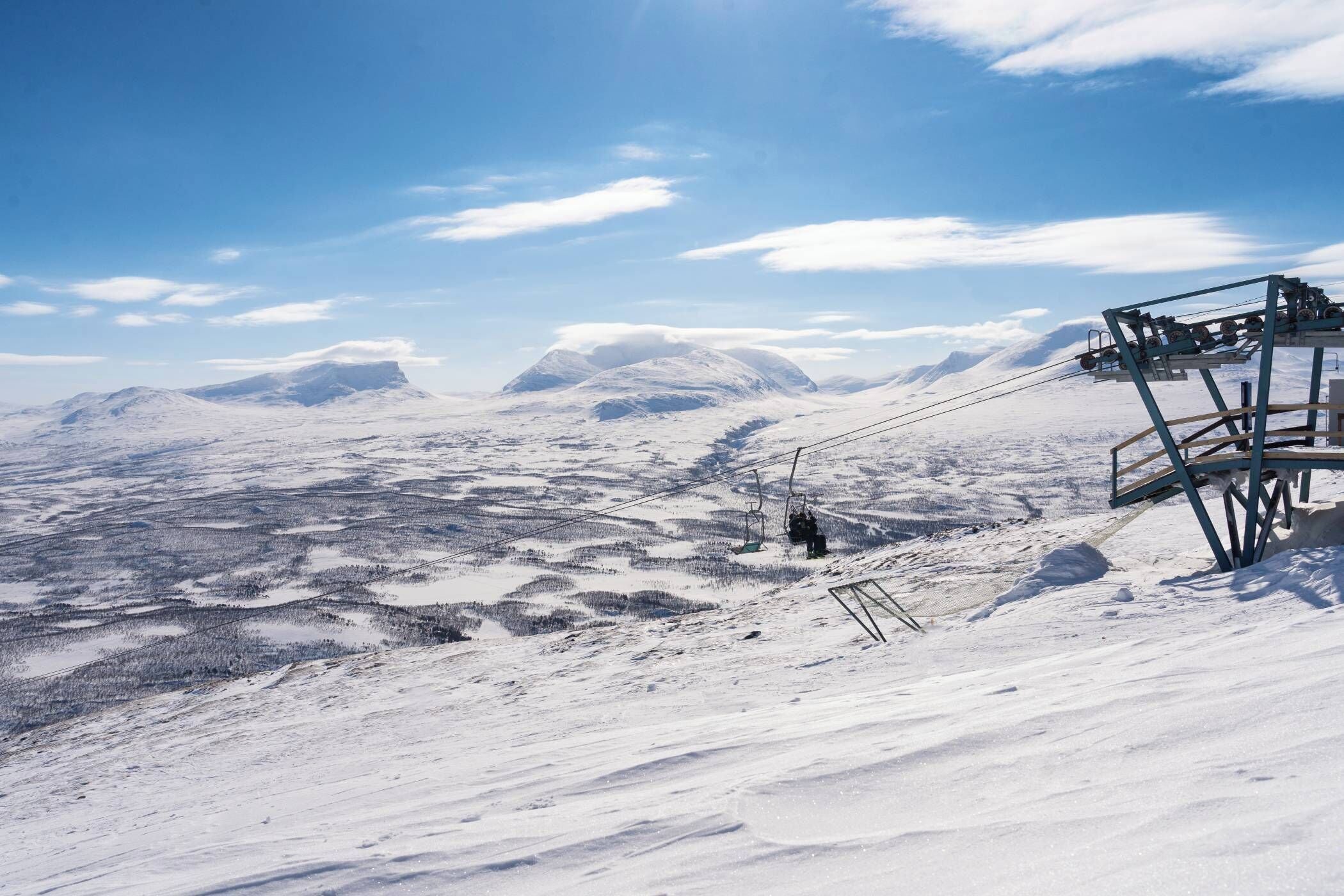 A snow-covered mountain landscape with a ski lift and a chairlift.