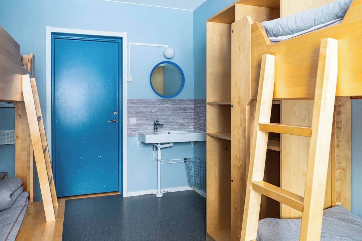 A compact room with a blue door, a sink, and a bunk bed.