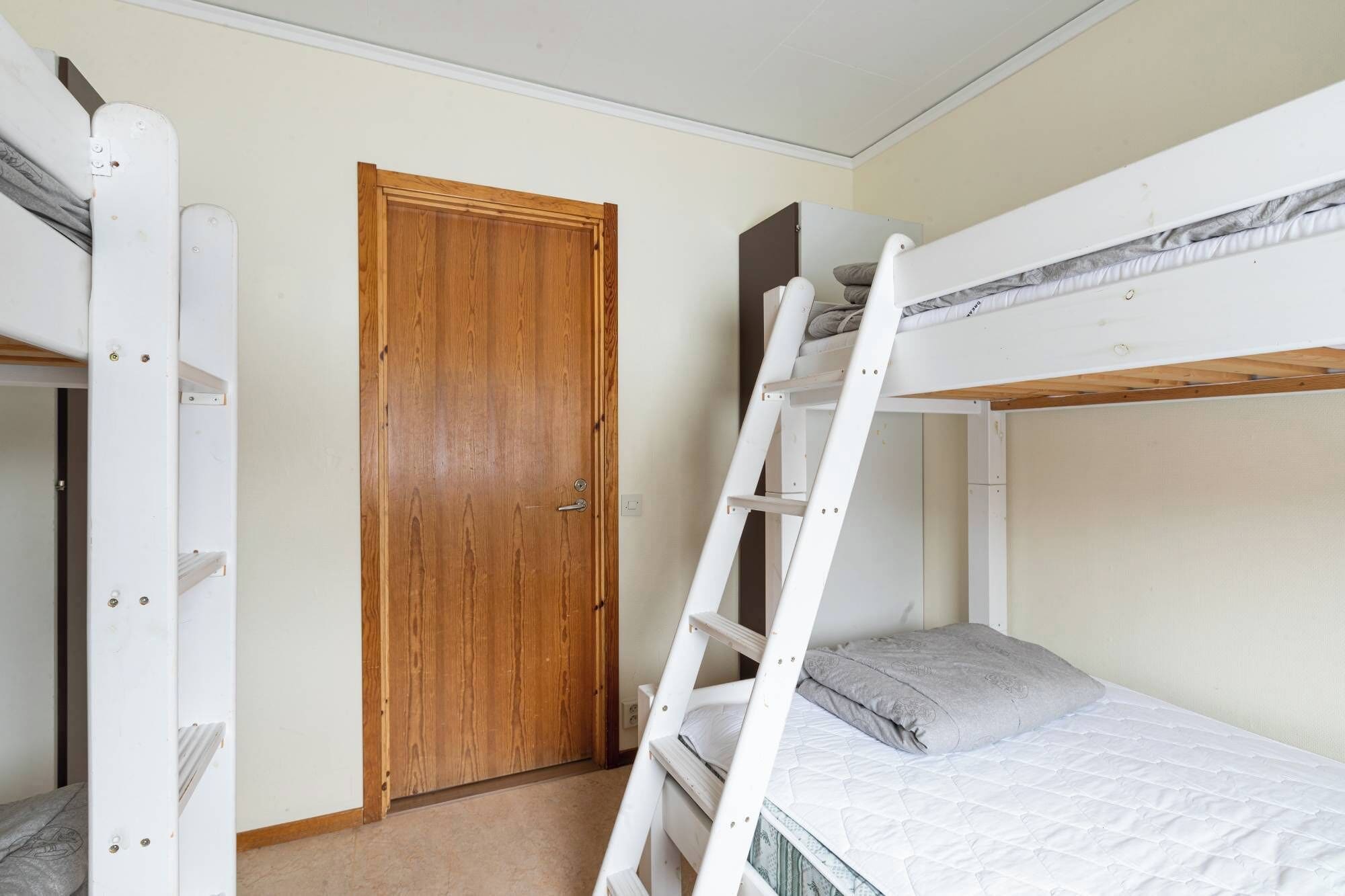 A bunk bed room with a wooden door and a white ladder.