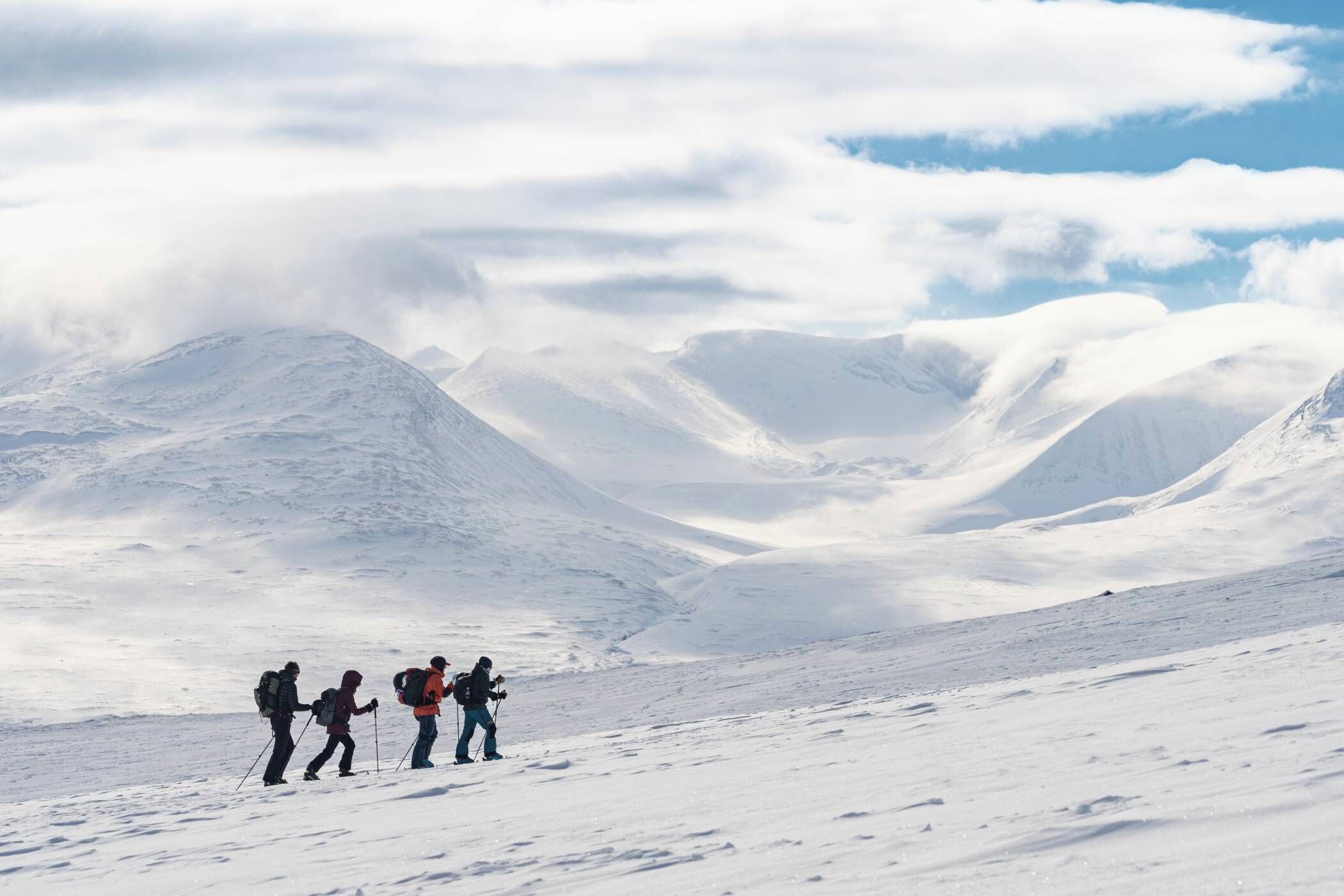 Un grupo de excursionistas en un sendero montañoso cubierto de nieve.