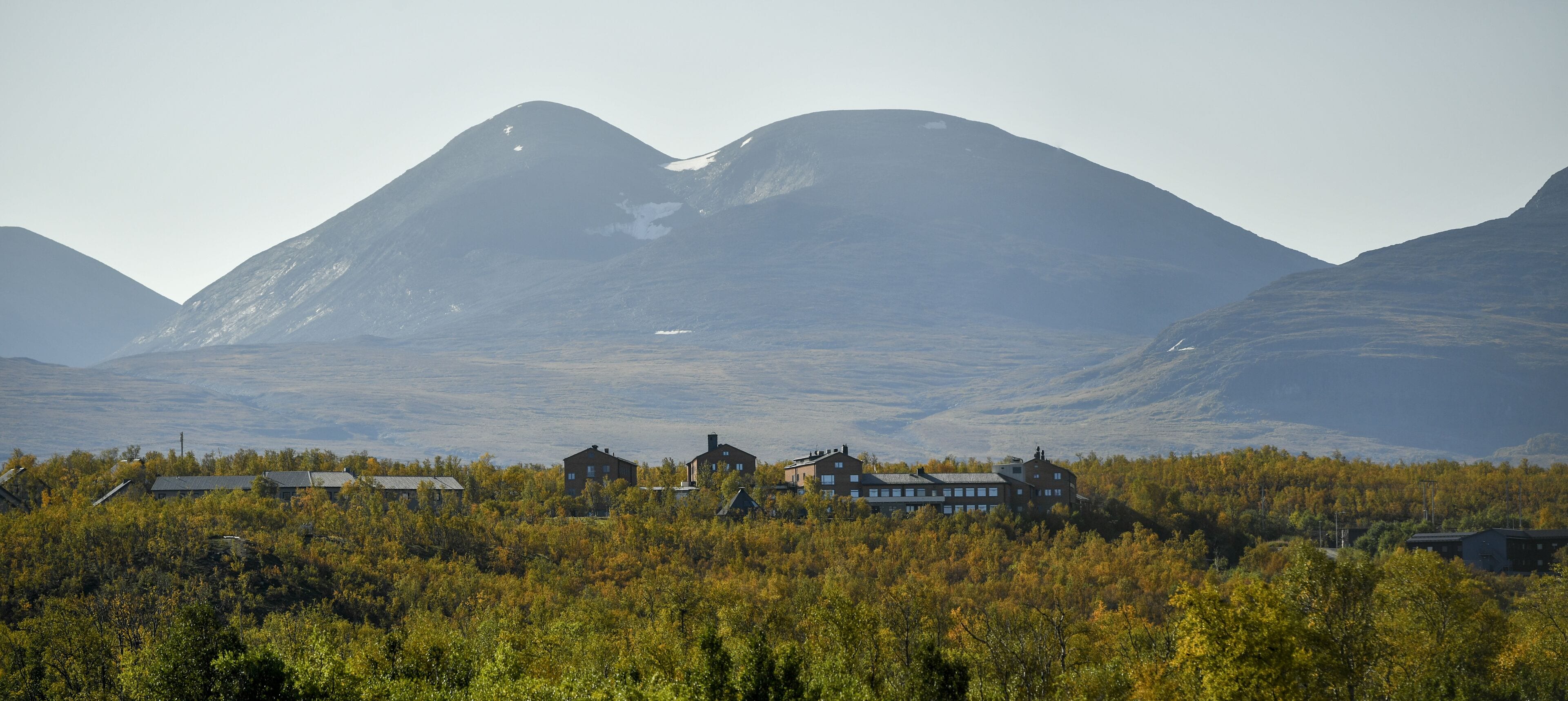 A mountain landscape with a cluster of buildings in the foreground.
