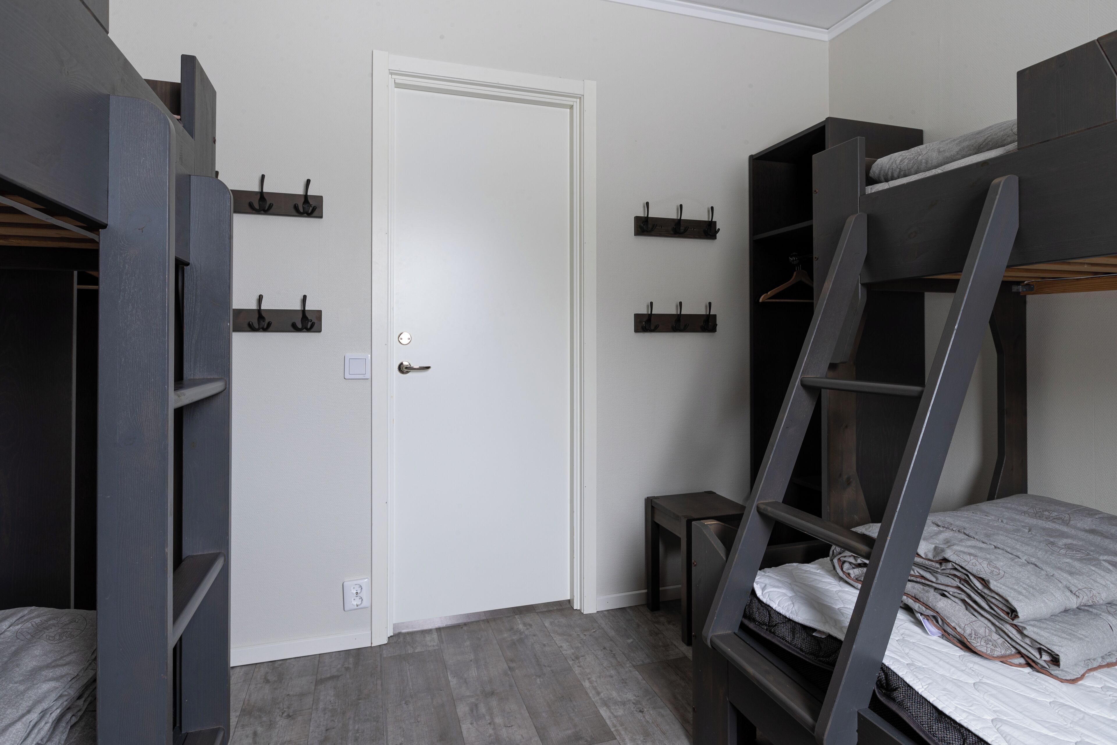 A room with bunk beds, a door, and a small table.