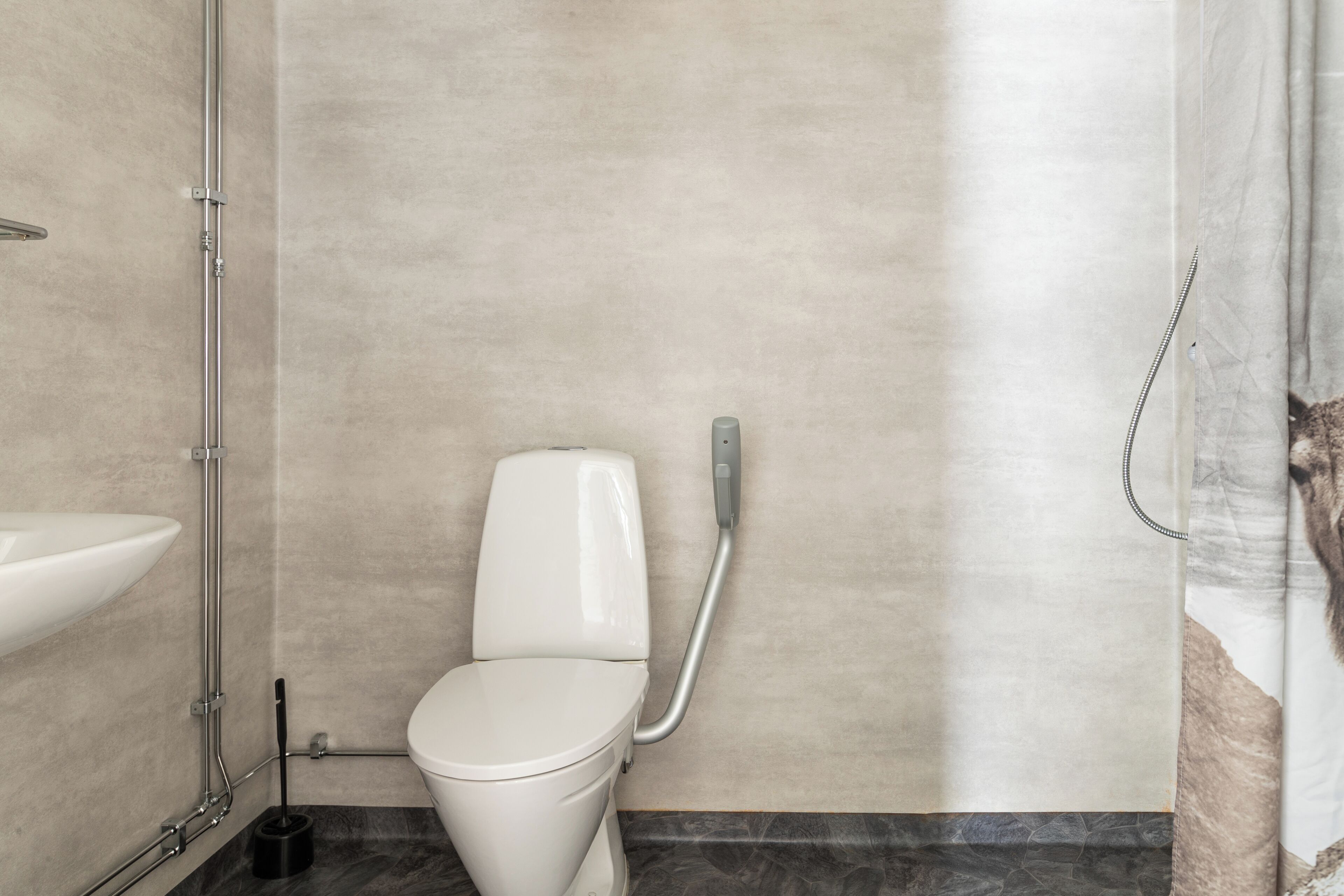 Une salle de bain avec des toilettes blanches, un lavabo et une douche.