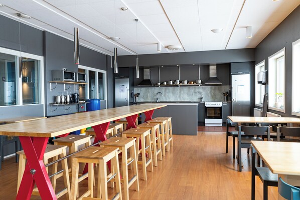 Una cocina moderna con una mesa de madera larga y taburetes de bar, equipada con electrodomésticos de acero inoxidable y una isla grande.