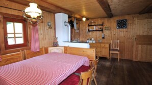 A cozy wooden cabin with a dining area, a kitchen, and a bed with a checkered bedspread. - Chalet in Obervellach in Carinthia (Obervellach)