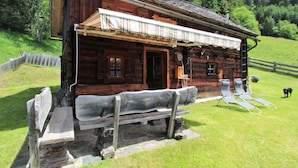 A rustic wooden cabin with a wooden bench outside, a dog in the background, and a wooden fence. - Chalet in Obervellach in Carinthia (Obervellach)