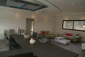 Una sala de estar moderna con una isla de cocina, zona de estar y ventanas amplias.