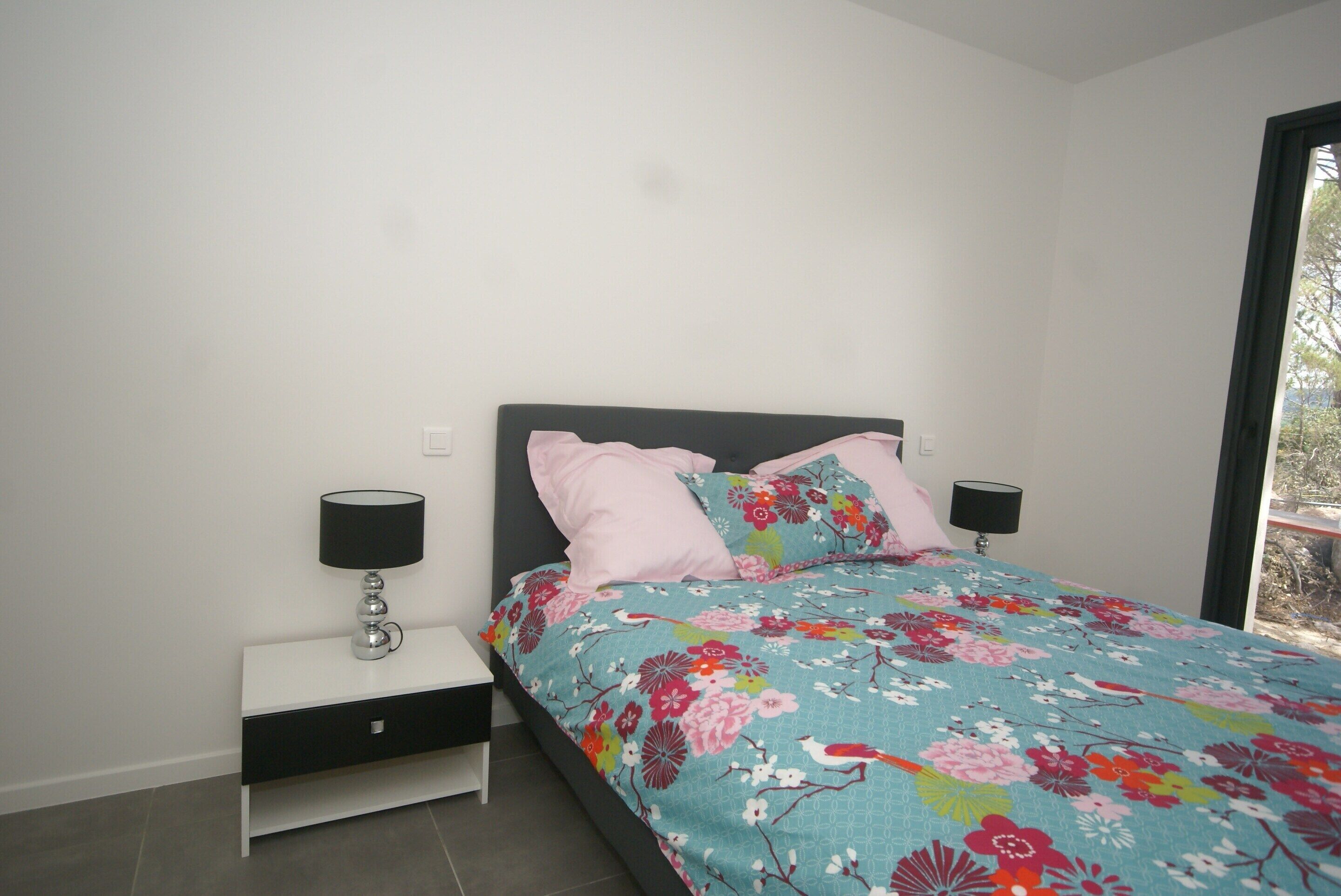 A bedroom with a bed, two bedside tables, and a window.