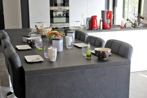 Una cocina moderna con una isla central, zona de estar y varios electrodomésticos.