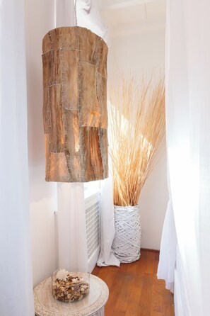 Una habitación con panel de madera, un florero de vidrio con plantas secas y una pequeña mesa redonda con un objeto decorativo.