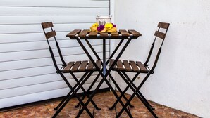 Une petite table d’extérieur avec deux chaises, un panier et quelques fleurs.