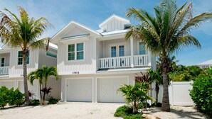 A two-story house with a white exterior, a balcony, and a garage. - Island Charm, Luxury Location & Pet Friendly (Holmes Beach)
