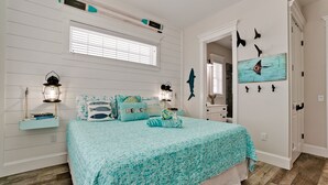 A bedroom with a bed, a window, a wall-mounted shelf with books, a wall clock, and a painting. - Island Charm, Luxury Location & Pet Friendly (Holmes Beach)