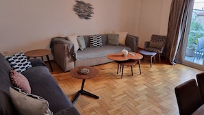 A modern living room with a grey sofa, a patterned armchair, and a small round table. - "Your Home @Acropolis Museum" by YHA (ΑΘΗΝΑΙΩΝ)