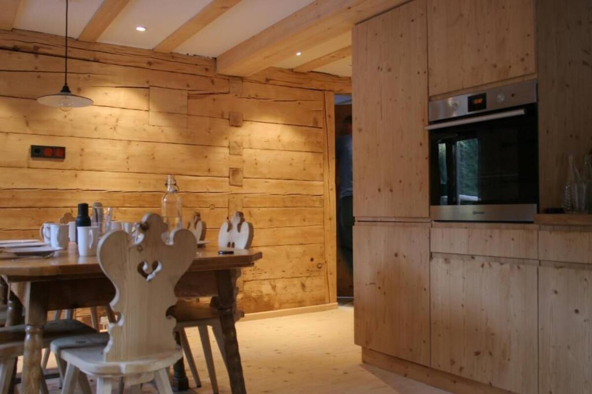 Un interior de madera con una mesa de comedor, sillas y un horno empotrado.