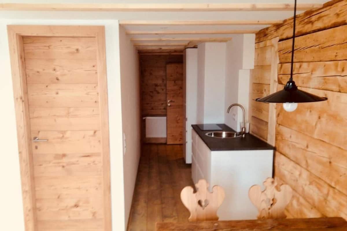 Un interior de madera con cocina, que incluye un lavamanos y una lámpara colgante.