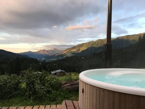 A hot tub on a wooden deck with a mountainous landscape in the background. - Bergheim Waeldele (Mittelberg)