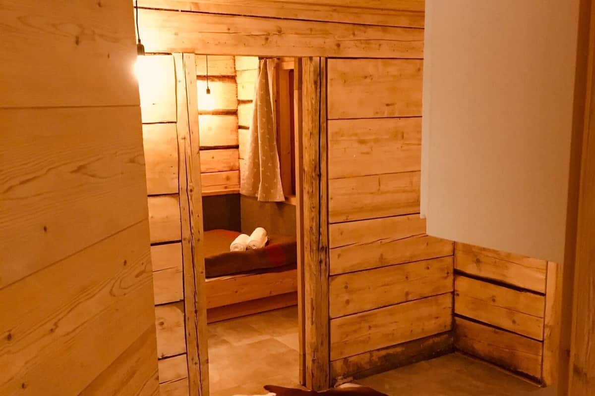 Interior de una cabaña de madera con zona de sauna, que incluye un banco y suelo con calefacción.