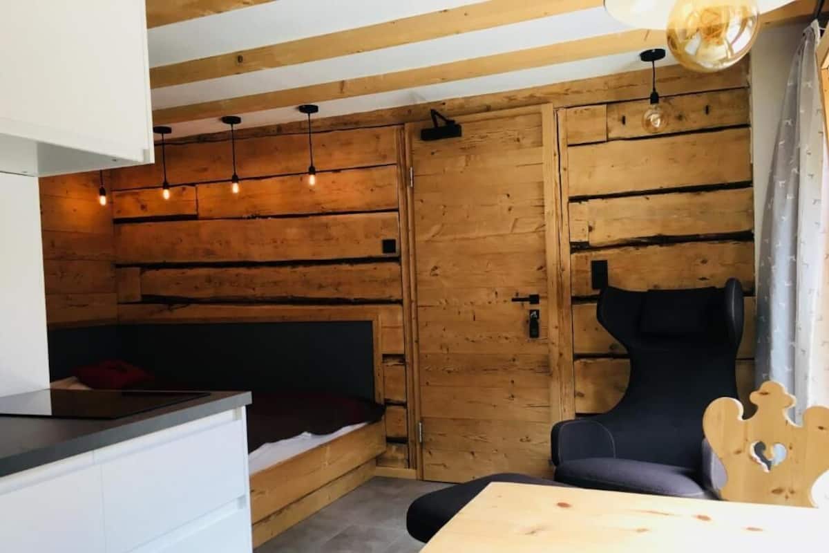Una habitación acogedora con cama, una silla, una mesa y paredes de madera.