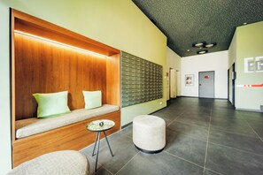 A modern lobby with a wooden bench, a wall-mounted mail slot, and a tiled floor. - Brera Serviced Apartments Ulm (Ulm)